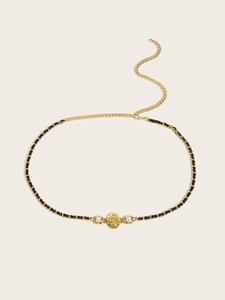Detail of gold chain belt featuring a lion head buckle with pearls and black leather