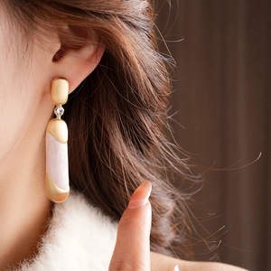 Dettaglio di orecchini vintage in oro opaco con cilindro rosa e pietre di zircone