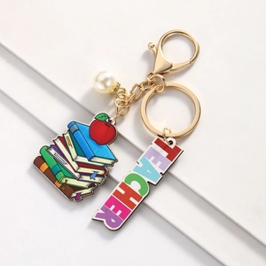 Detail of teacher keychain with book, apple enamel charms and engraved metal bar
