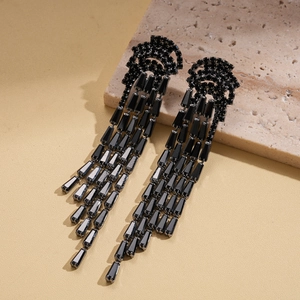 Detailed view of black zircon jellyfish tassel earrings displayed on a textured stone