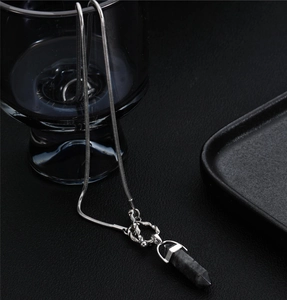 Close-up of titanium steel snake chain with a black hexagonal stone pillar pendant
