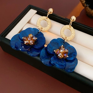 Macro detail of vintage blue flower earrings with gold crystal center on jewelry display