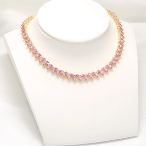 Pink heart crystal necklace set on white bust display with gold tennis chain detailing