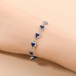 Vue détaillée d'un bracelet à pierres bleues en forme de cœur serties sur le poignet