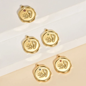 Close-up of golden round pendants with baby hand and footprints and colorful crystals