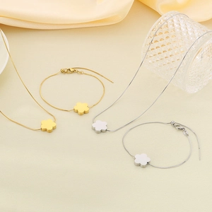 Close-up of gold and silver stainless steel clover pendant necklaces and bracelets on fabric