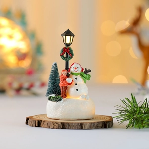 Luminous Christmas miniature with snowman, street lamp, and boy on a wood base
