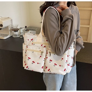Detail of canvas tote bag with cherry print showing side pockets and large capacity