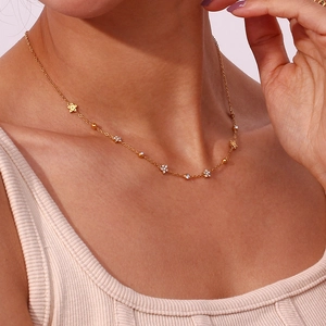 Detail of a gold necklace featuring dainty flower pendants with sparkling zircon stones