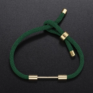 Detail of dark green braided rope bracelet with adjustable gold slide buckle and metal bars