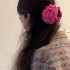 Detail view of large pink fabric rose flower hair claw clip worn on long hair side