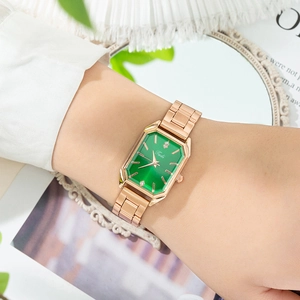 Montre quartz octogonale en or rose avec cadran vert émeraude sur un poignet féminin