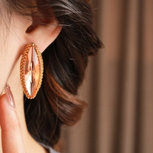 Macro side view of amber marquise-cut crystal earrings with golden beaded edging details