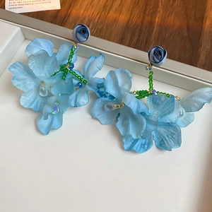 Close-up of light blue fabric flower earrings with crystal drops and beaded stems