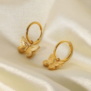Close-up of 18K gold plated butterfly drop earrings on soft cream satin fabric