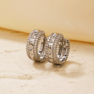 Macro detail of silver hoop earrings with micro-set zircons and geometric studs