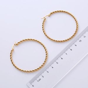 Golden 50mm twisted rope hoop earrings displayed with transparent ruler for size