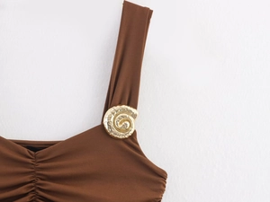 Detail showing elegant golden shell-shaped metal buckle on a brown dress strap
