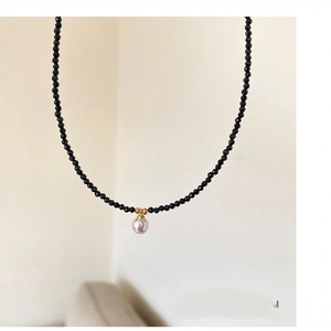 Vue détaillée d'un collier de perles de cristal noir avec un pendentif perle rose