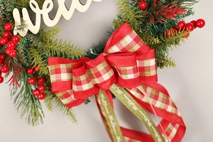 Macro detail of Christmas wreath featuring red berries and Merry Christmas ribbon bow