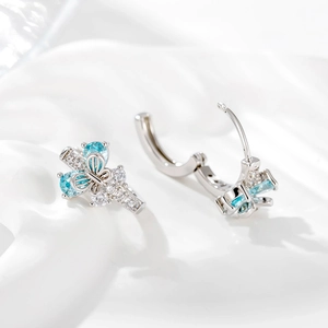 Boucles d'oreilles nœud en argent avec pierres bleues et croix sur soie blanche
