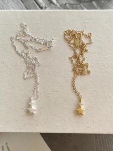Detailed overhead view of brushed gold and silver star necklaces with zircon accents