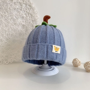Detail of baby knitted blue pumpkin hat with green leaves and a small baby label