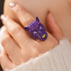 Vue détaillée d'une bague tête de panthère violette à pois roses portée à la main