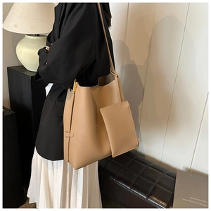 Close-up of khaki pebbled leather bucket bag with metallic buckle and matching zip pouch