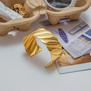 Modern wide gold-plated open bangle with twisted wavy texture and high-shine finish