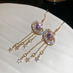 Detail of gold star tassel earrings featuring a pink gemstone and shimmering micro-zirconia