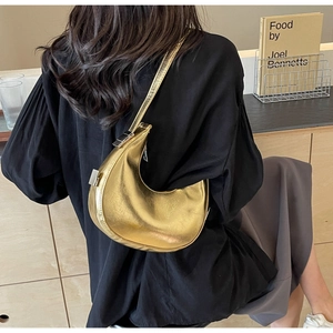Close-up of champagne gold crescent underarm bag with pleated leather and silver zipper