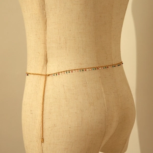 Detail of golden waist chain with colorful pendants on a model for bohemian style