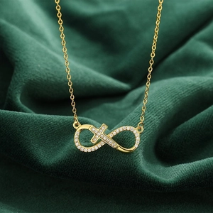 Collier pendentif croix infini en or serti de zircons blancs sur fond en velours vert