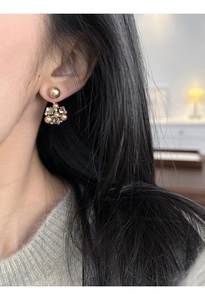 Close-up of elegant gold flower earrings with pearls on model's ear for classic style