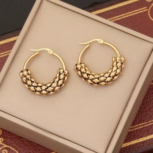 Macro shot of gold beaded round earrings resting in a beige jewelry box tray