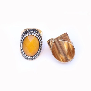 Macro detail of wide gold ring featuring faceted yellow stone and textured band