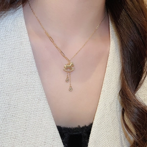 Detailed view of a gold plated necklace with a small rocking horse pendant and zircons