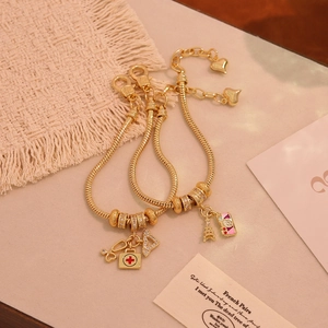18K gold plated snake chain bracelet featuring medical and travel theme charms