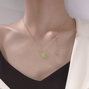 Close-up of Hetian Jade pendant necklace with gold chain and heart charm on a model