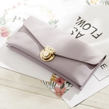 Close-up of light purple PU leather wallet with a golden twist lock on a white table