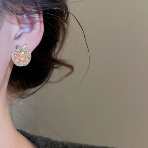 Close-up of sparkling apple earrings with zircons on a model's ear showing elegant details