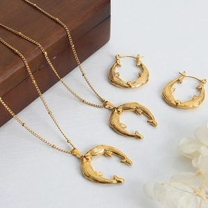 Gold dolphin necklace and earrings set on white wood background with a dark wooden box