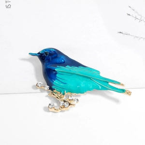 Minimalist enamel bird brooch on a golden rhinestone branch with blue gradient finish