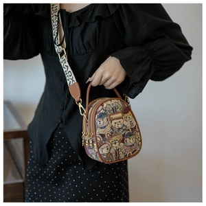 Detail of crossbody bag with teddy bear print, brown leather trim, and wide logo strap