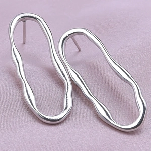Detailed view of silver 304 stainless steel wavy geometric hoop earrings on fabric
