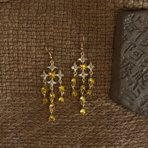Macro detail of vintage gold starburst earrings with sparkling rhinestones and tassels