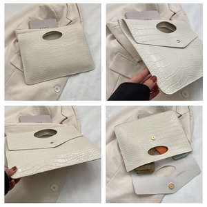 Detail view of white crocodile pattern envelope clutch with magnetic closure and oval handle