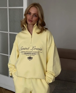 Detail of yellow sweatshirt featuring half-zip high neck and Saint Louis embroidery