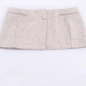 Jupe courte en tweed beige pour femme avec bouton décoratif et texture de tissu